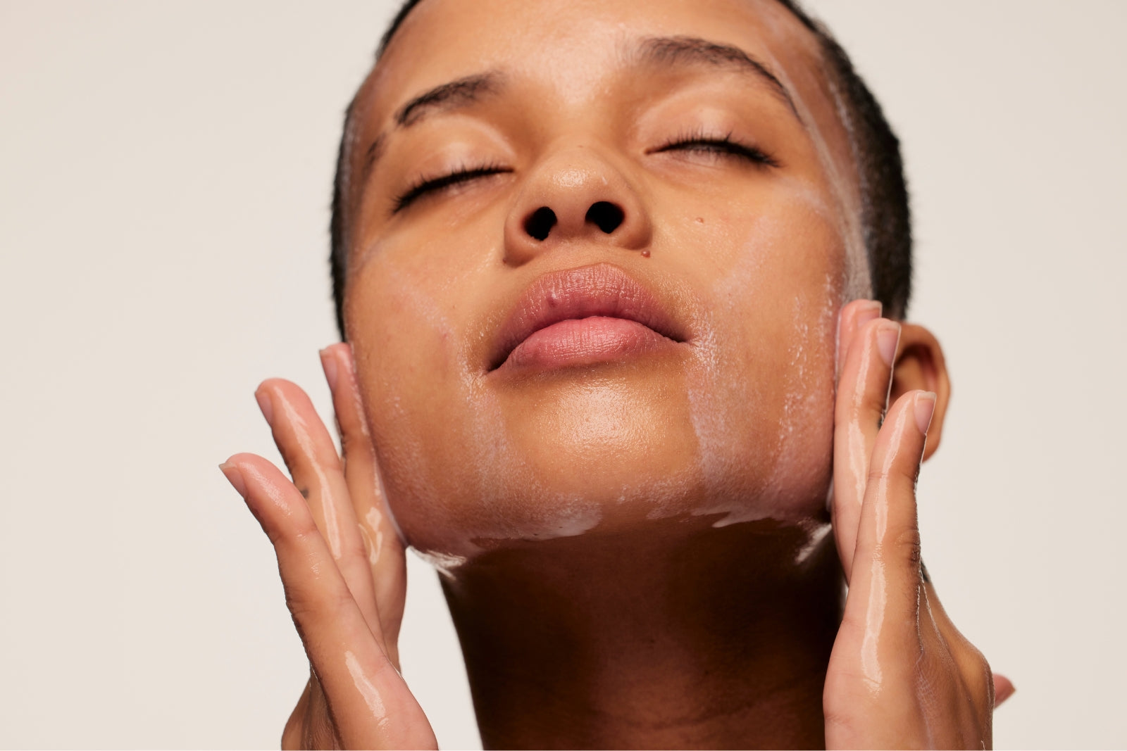 Woman enjoying a mindful cleansing moment while washing her face with Daily Meltdown cleansing balm