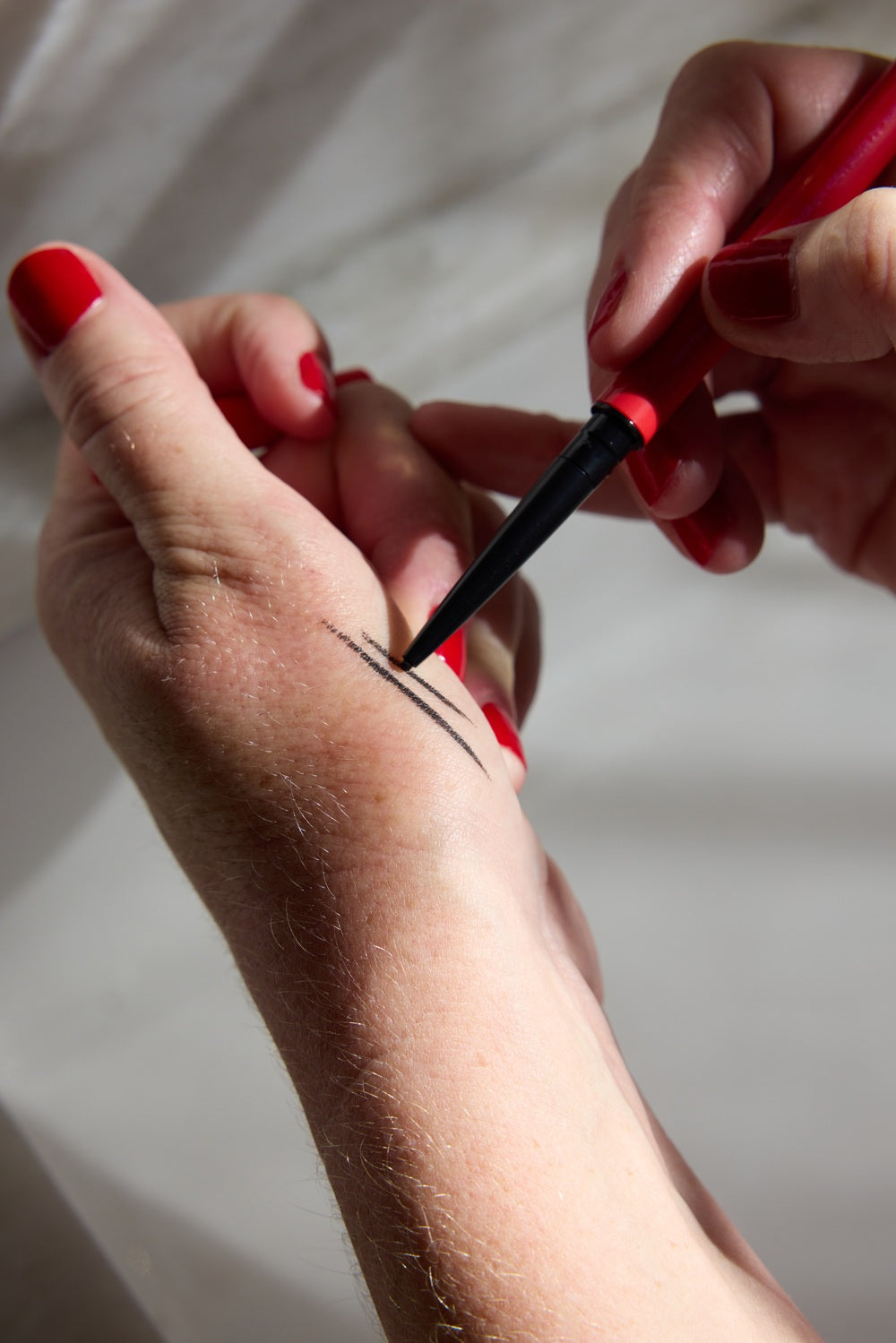 Person testing eyeliner define me in the hand to see the lines.